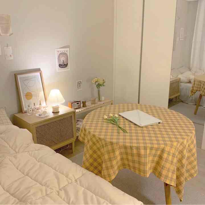 Yellow plaid tablecloth on a round table in a natural tone living room, cozy space with beige sofa and wooden storage cabinet