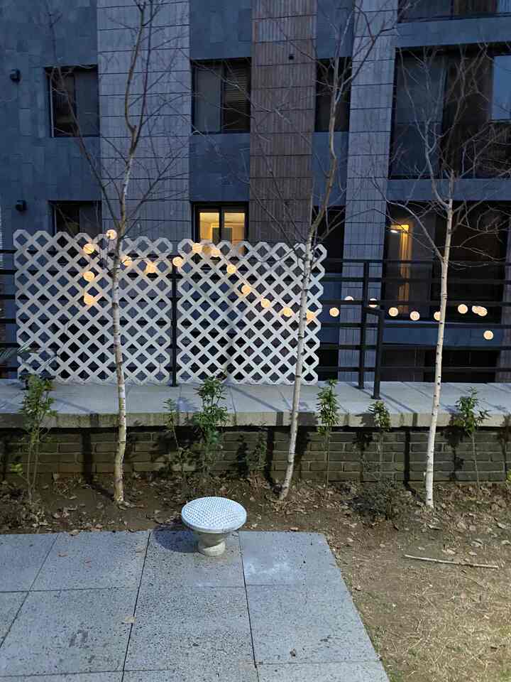 夕暮れの都市テラス、柔らかい白い格子と屋外照明が配置された空間