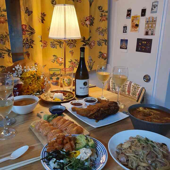 Yellow floral curtains and wood-tone dining table in dining room featuring wine glasses and party food for cozy home party setting