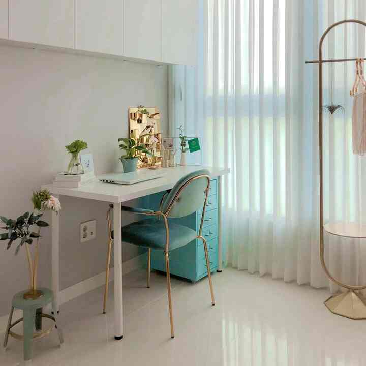 ミントとゴールドのアクセントがある小さな作業スペース、ホワイトカーテンと整ったレイアウトのモダンな雰囲気