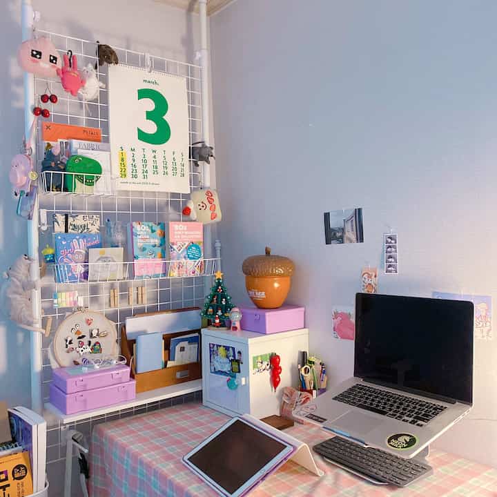 Pink and white toned compact home office with desk and laptop stand in a cozy kids' room setup