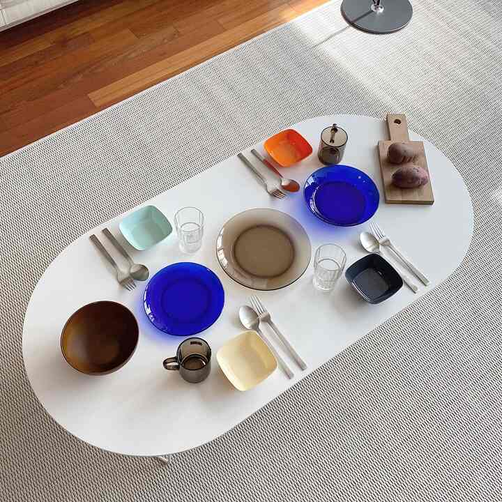 A white oval dining table featuring colorful plates and kitchenware in a natural modern style space
