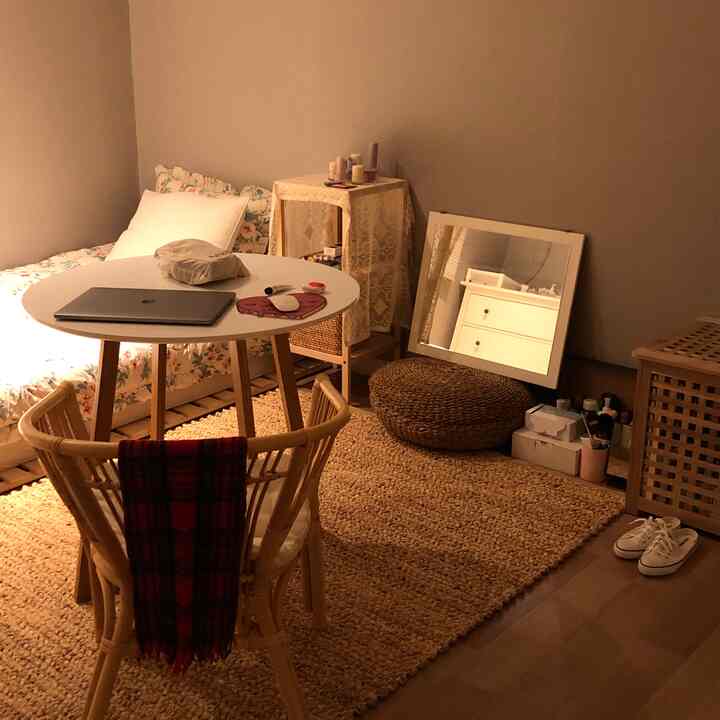 Warm beige natural-toned bedroom featuring a round table and rattan chair, creating a cozy home office and relaxation area