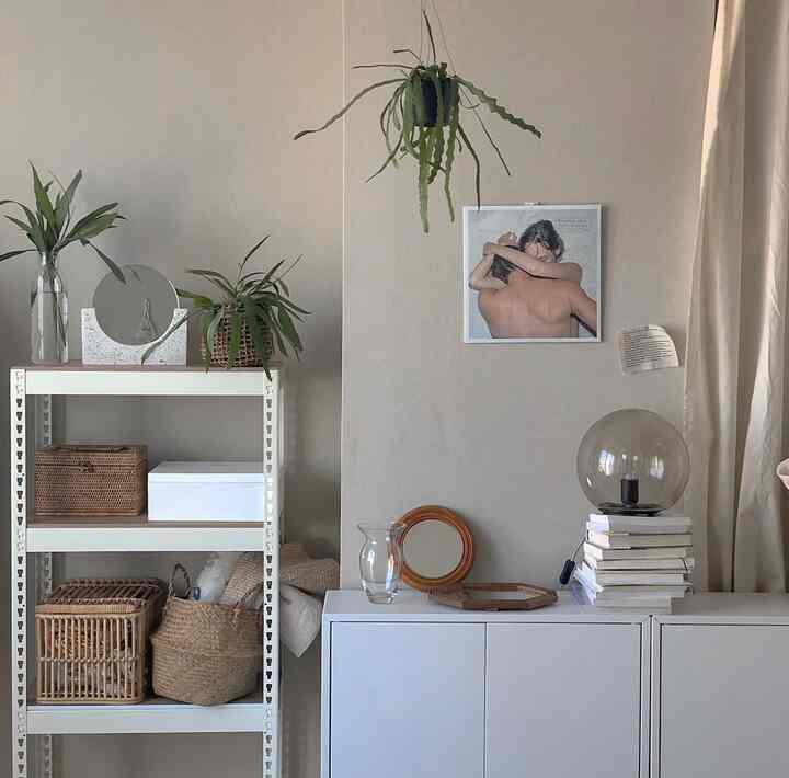Beige-toned wall with white storage cabinets, rattan baskets, and plants in a simple and natural living space
