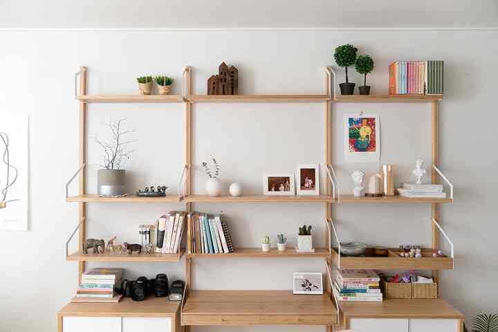 Simple living room with white walls and natural wood-tone SVALNÄS bookshelf arranged neatly