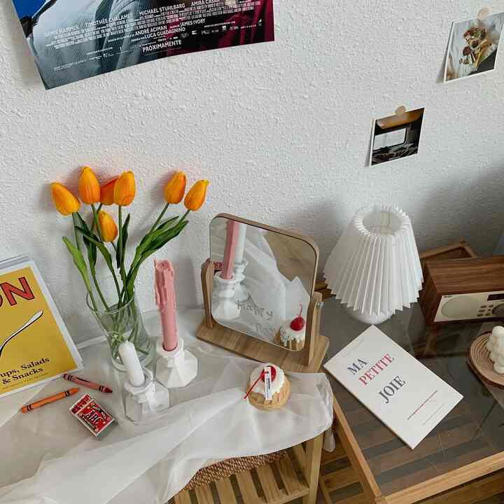 Natural wood tones and white lighting define a cozy studio vanity area, accented by yellow tulips and candles enhancing a spring vibe