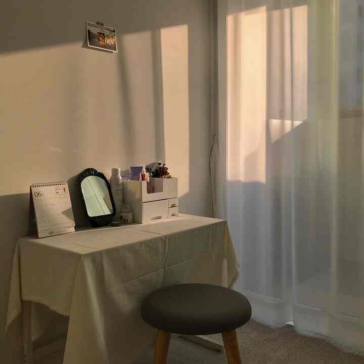 Warm beige-toned bedroom veranda space featuring a small desk used as a vanity and chiffon curtains, creating a cozy atmosphere