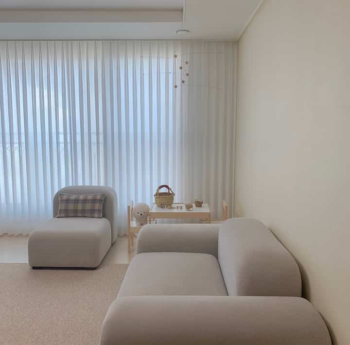 Beige and white toned living room featuring gray fabric sofa and kids' table set with a natural modern style