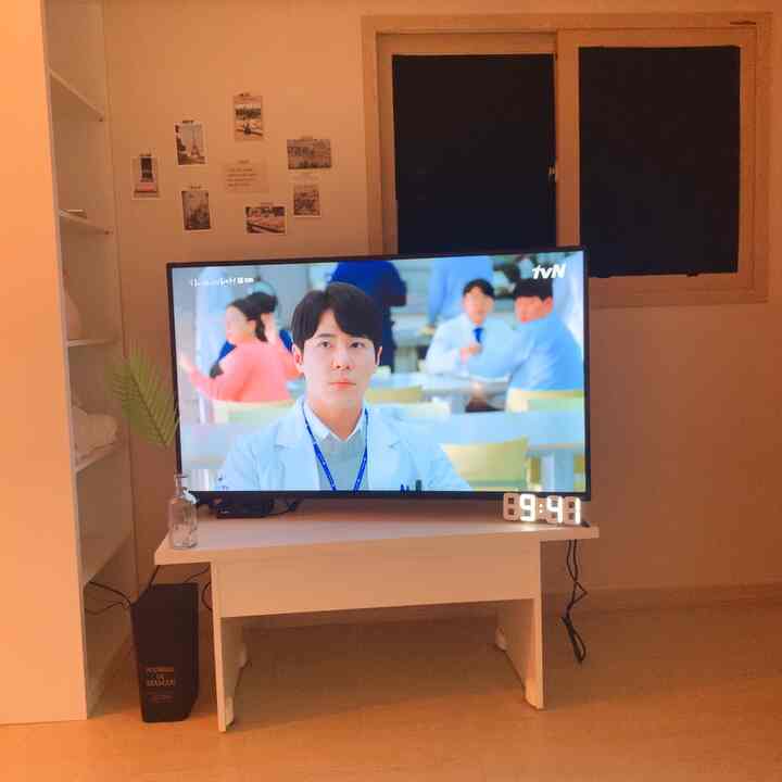 Warm white and natural-toned living room featuring TV stand with LED clock and Paris-themed postcards creating a cozy atmosphere