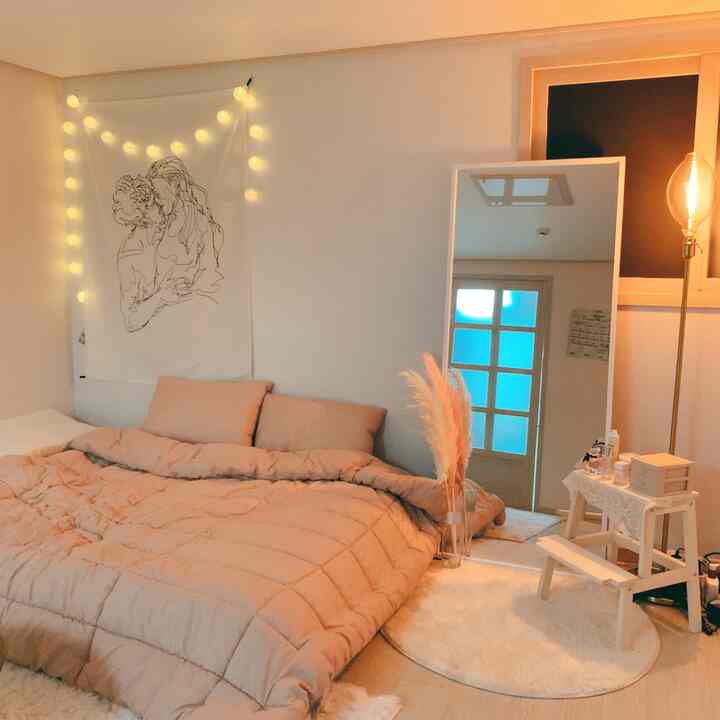 Beige-toned single bedroom featuring a large mirror and small stool creating a cozy resting space