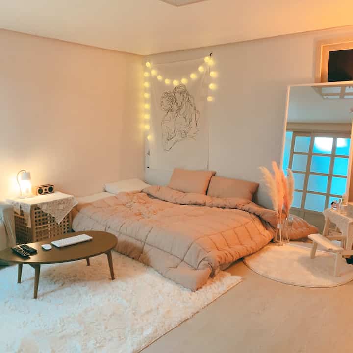 Warm beige-toned studio bedroom and living room with soft plush rug, cozy and natural atmosphere