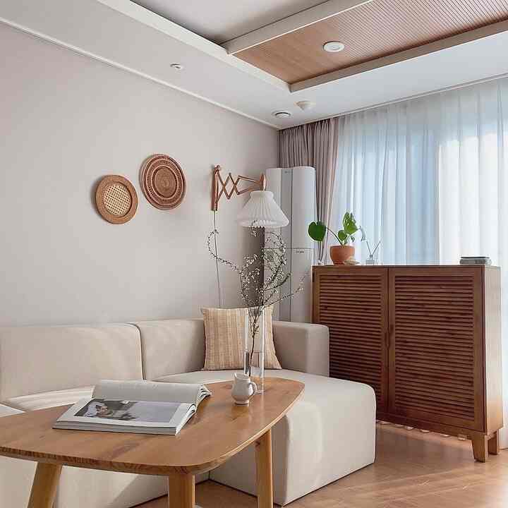 Natural wood tones and white harmonize in the living room, featuring a simple sofa and wooden coffee table in a cozy setting