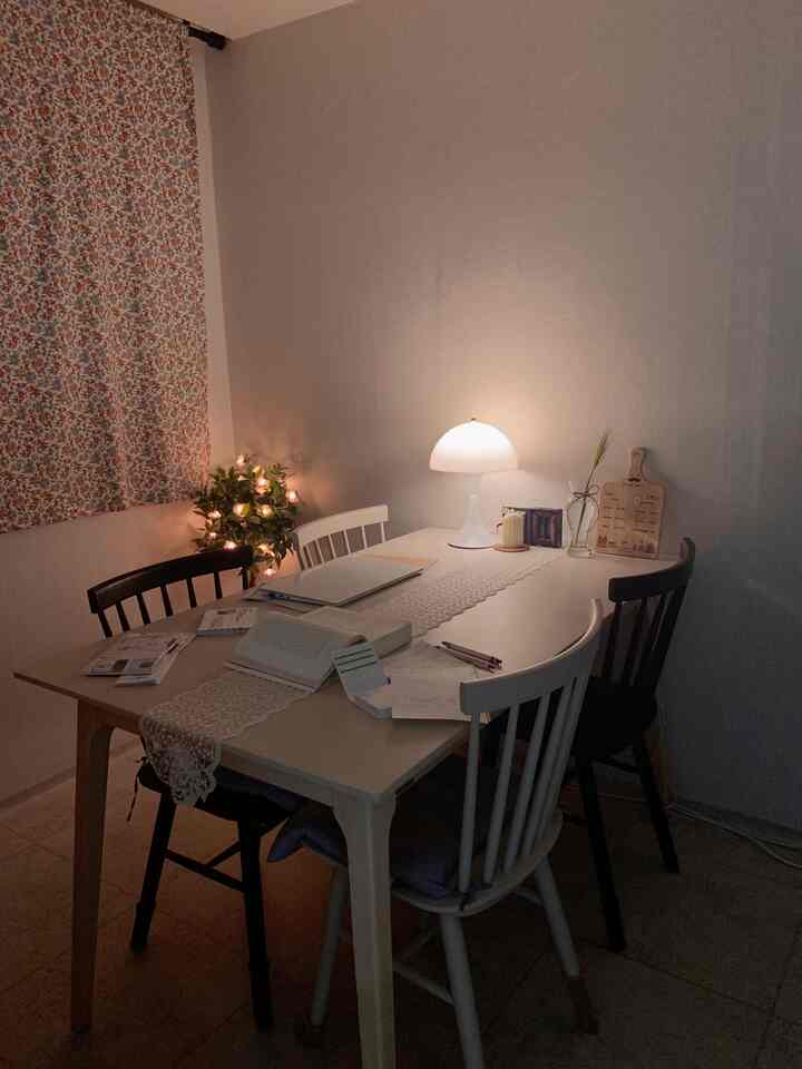 Cozy dining room with warm lighting and retro floral curtain, featuring a dining table and chairs arranged invitingly
