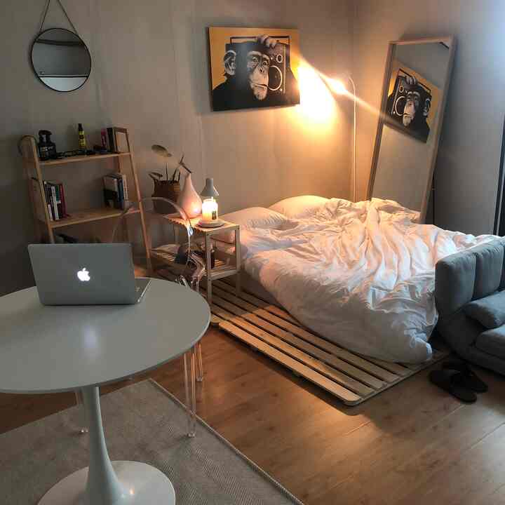 ナチュラルな木目調と白を基調としたシンプルな一人暮らしの寝室、デスクとフロアランプが在宅勤務に適した空間を演出