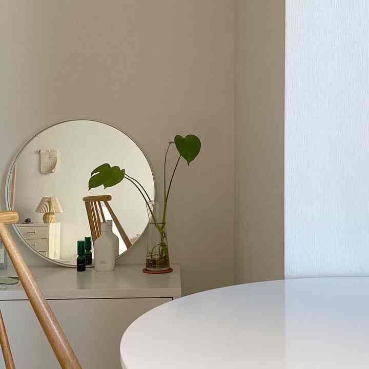 白と木目調の化粧台と丸い鏡が配置されたナチュラルなリビングスペース