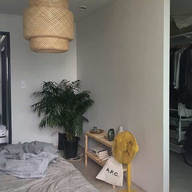 ナチュラルトーンの寝室とクローゼットが分かれた空間、木製棚とラタン製ペンダントライトが配置された落ち着いたインテリア