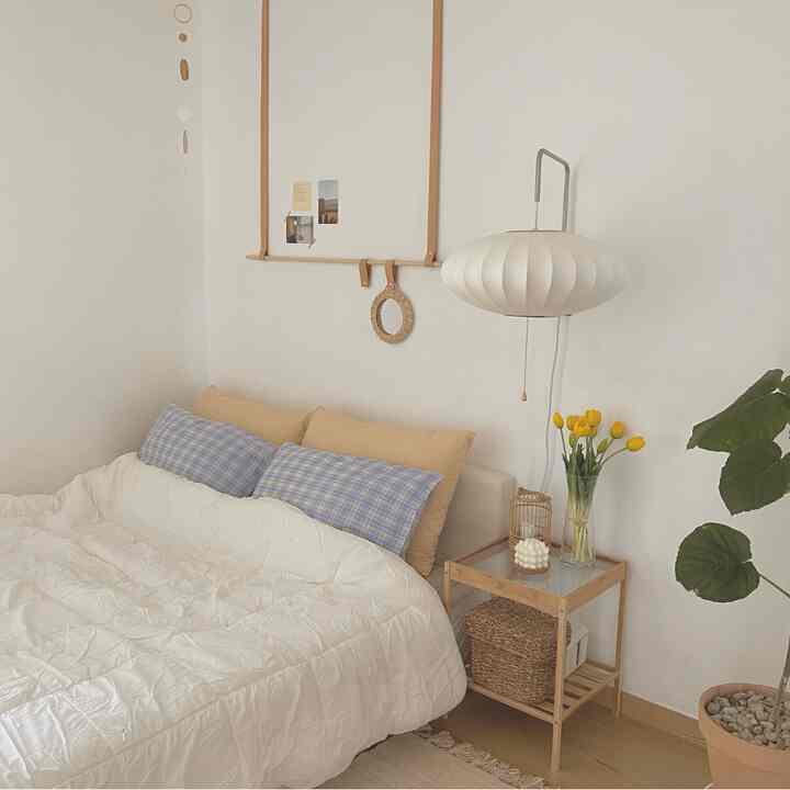 White and natural color bedroom featuring cozy bedding and wood-tone nightstand in a simple setting