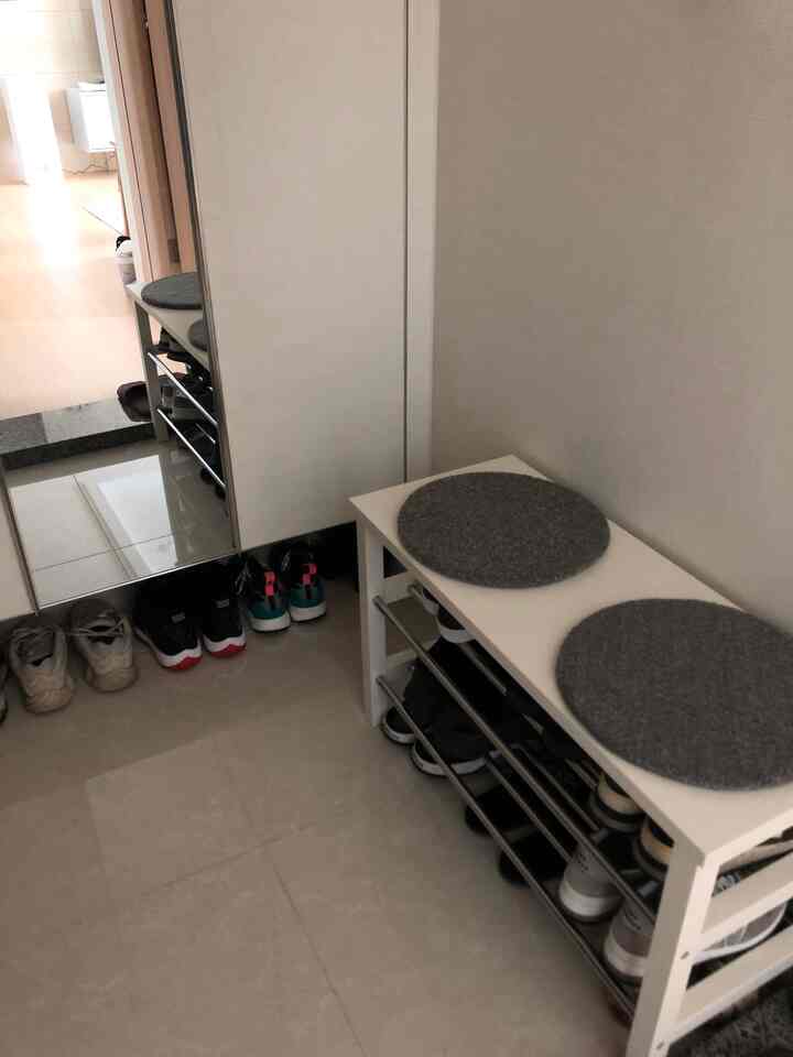 Clean entrance space with white floor and bench-style shoe storage cabinet