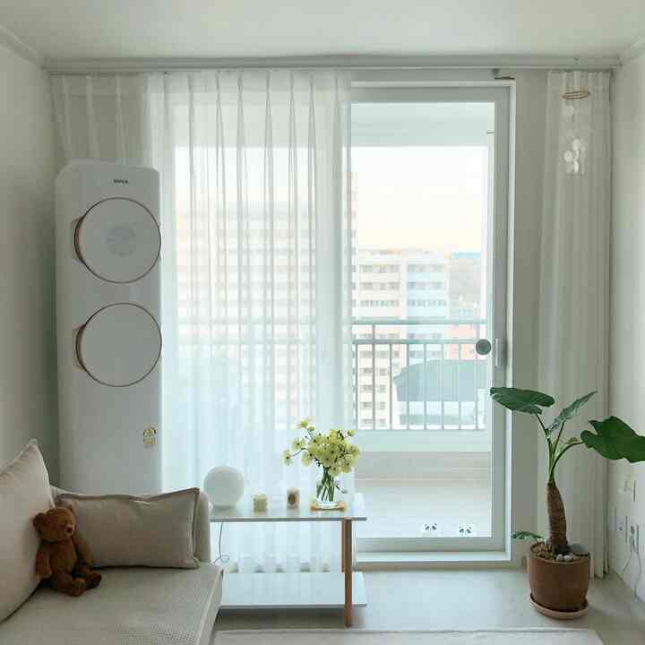 Bright, white-toned compact newlywed living room featuring sofa, shelf with flowers and candles for a simple, cozy atmosphere