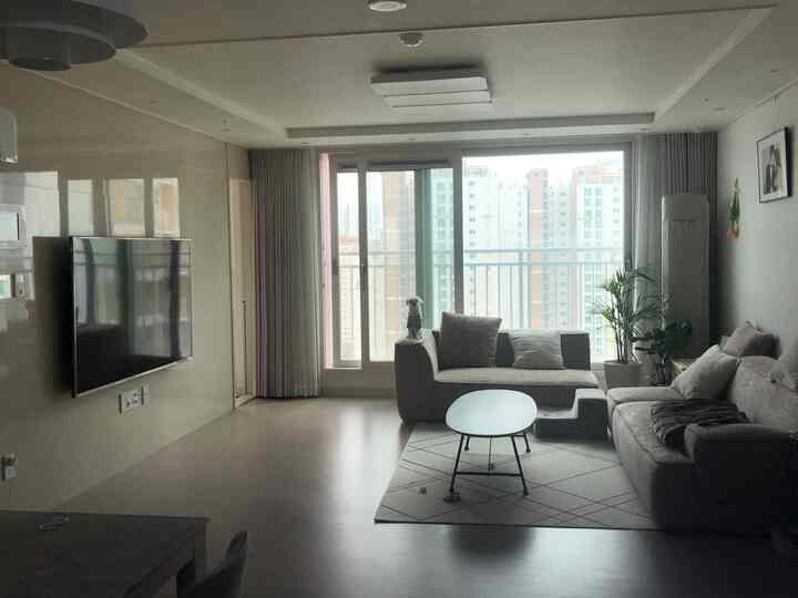 White and beige toned living room featuring beige sofas, Kai oval coffee table, cushions and plants in a cozy atmosphere