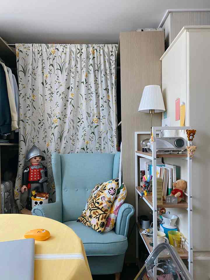 Light blue armchair with floral curtain in a compact living space
