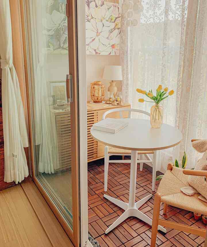 Warm white and beige toned veranda home cafe featuring a round table and storage cabinet with a simple interior