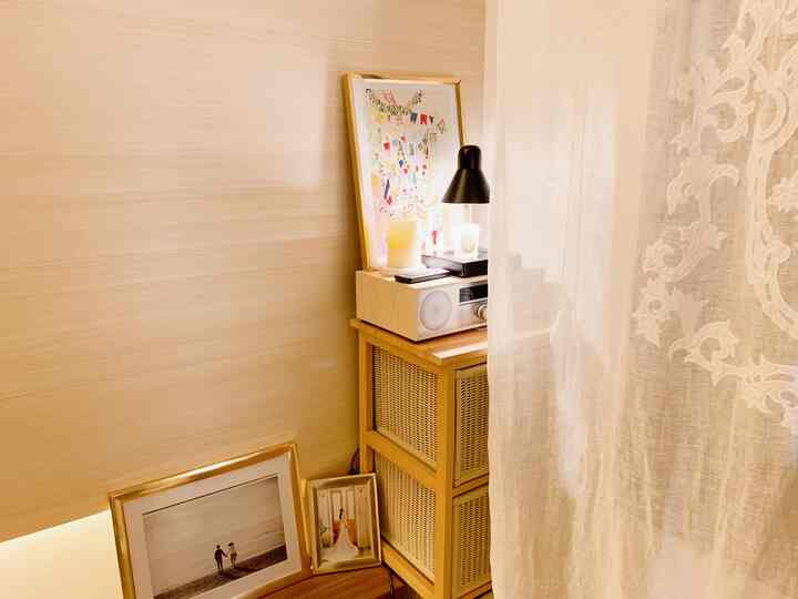Cozy natural living room corner featuring warm wood tones, gold picture frames, candle warmer, and radio with a serene atmosphere