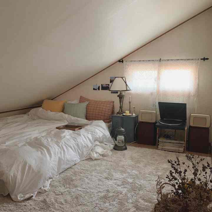Cozy loft bedroom with warm natural tones and white accents, featuring bed with pillows and cushions
