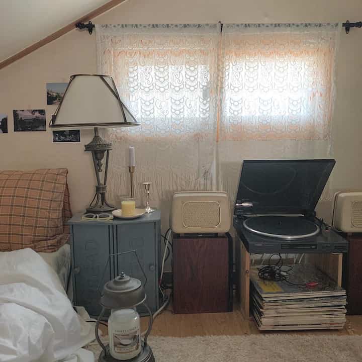Warm beige and wood-toned living room featuring vintage record player and lace curtains creating cozy atmosphere