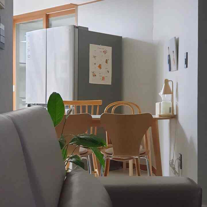 Bright white background kitchen featuring natural wood furniture and a variety of wooden chairs creating a cozy atmosphere