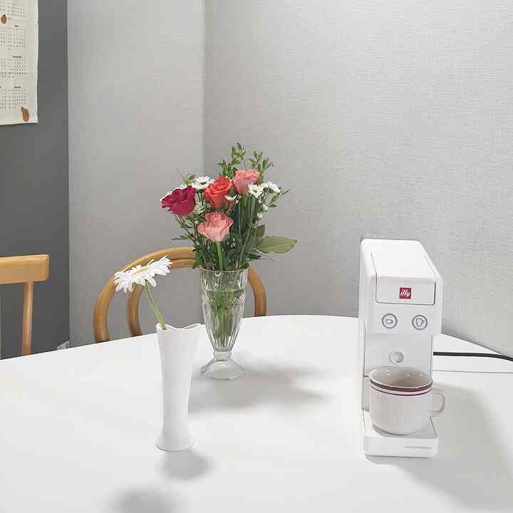 White and brown toned kitchen dining area featuring an illy coffee machine and fresh flowers creating a neat home cafe vibe