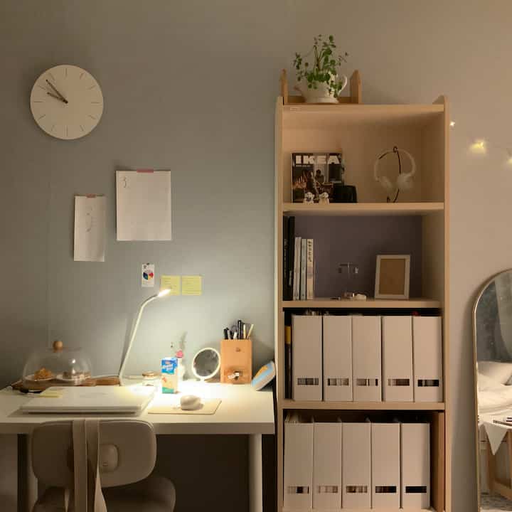 グレーの壁と白い家具が調和したシンプルなホームオフィス、机と整頓された本棚が配置された雰囲気のあるインテリア