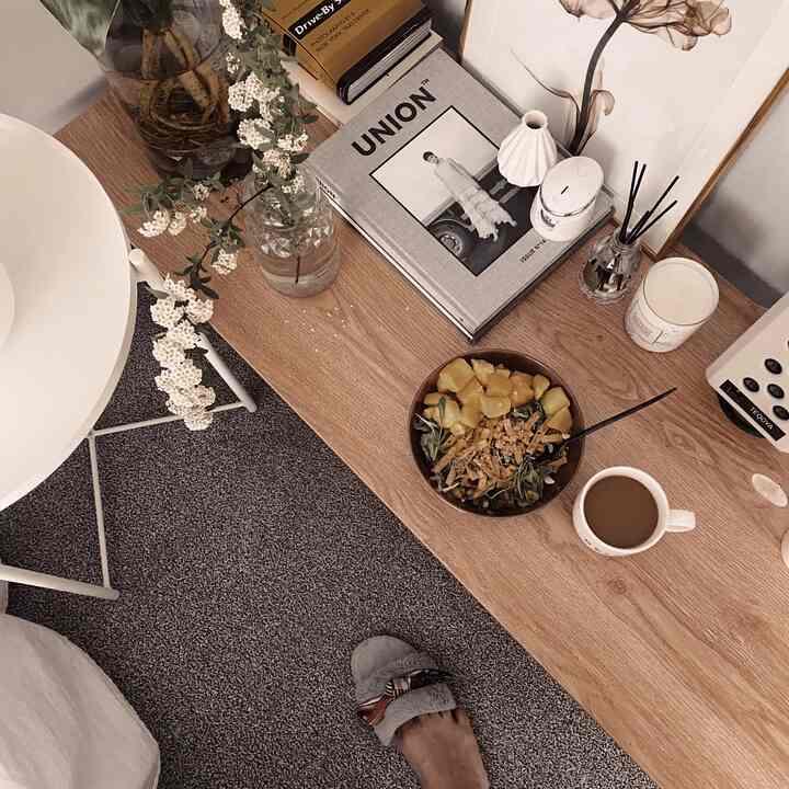 ナチュラルトーンの寝室、低い木製テーブルに花瓶、ディフューザー、キャンドル、サラダとコーヒーが配置された落ち着いた雰囲気のインテリア