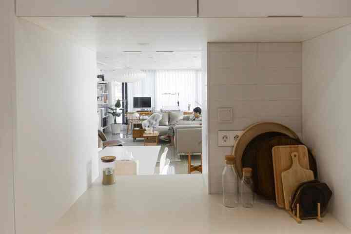White and wood tone open kitchen connected to living room in a natural modern style space