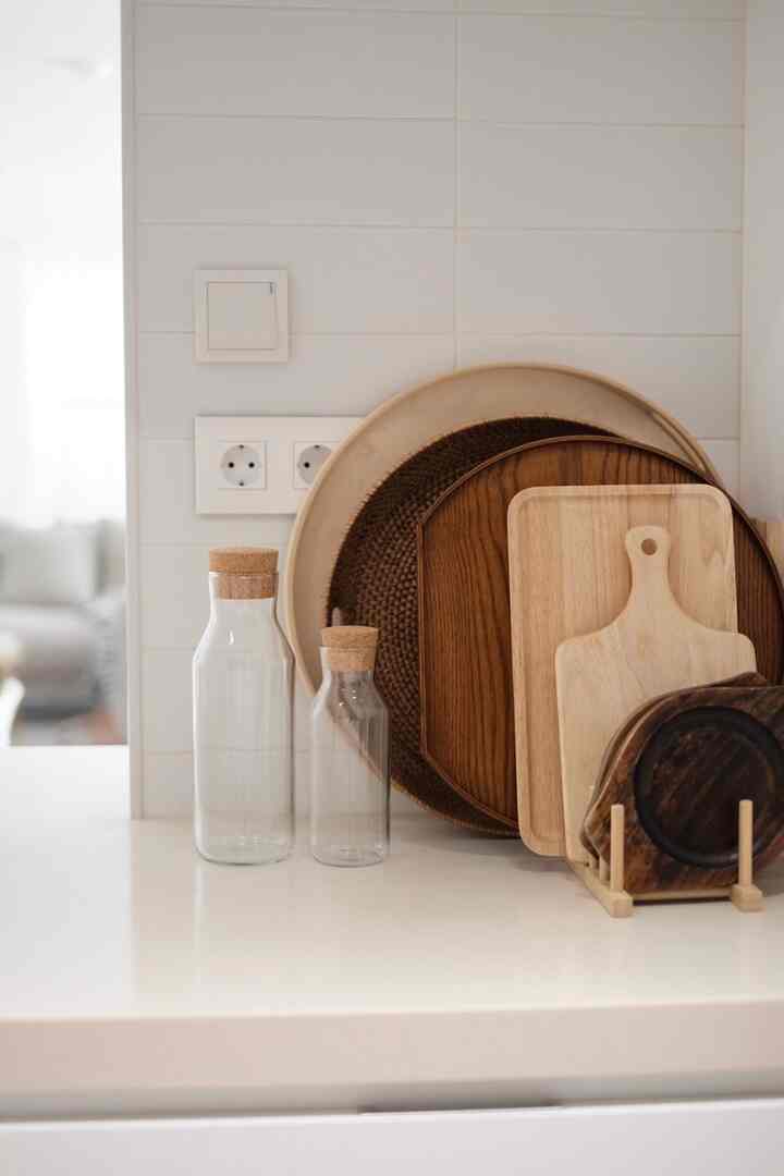 Natural color and white toned kitchen featuring wooden trays and glass bottles on a clean countertop