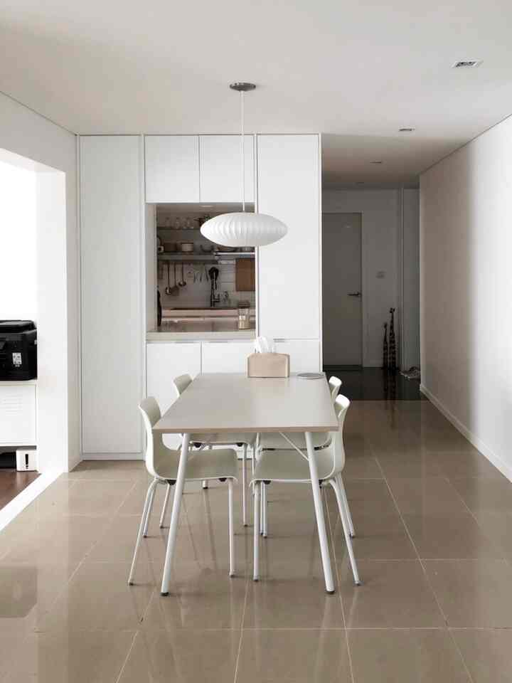 Modern dining room in white and beige tones featuring a white dining table and chairs in a clean space