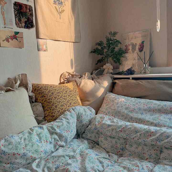 Beige-toned walls and white floral bedding create a cozy vintage bedroom space with decorative cushions and plants