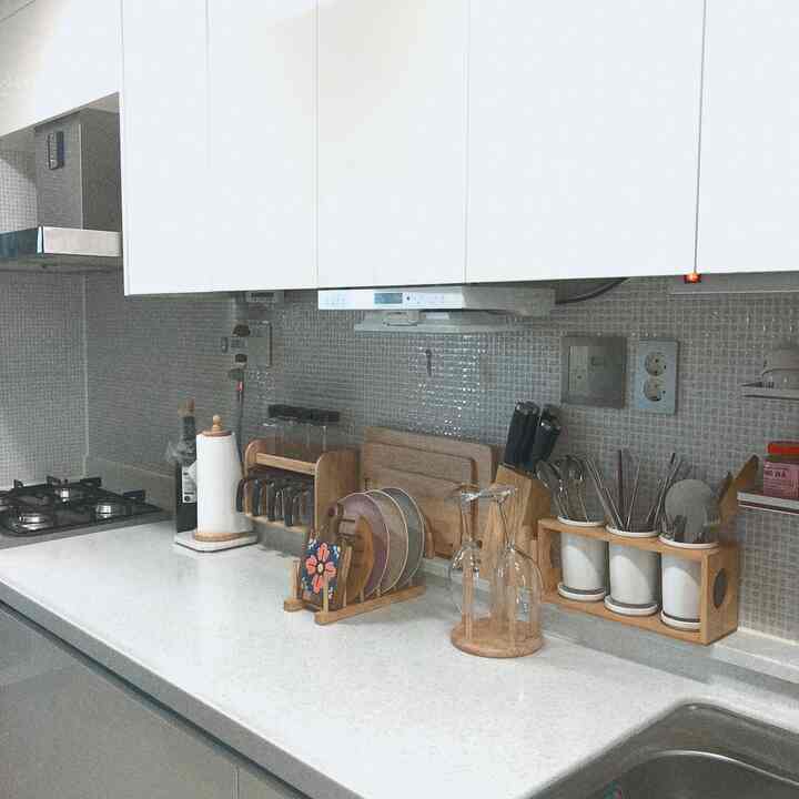 Bright white-toned kitchen featuring clean countertop with wooden kitchen utensils and accessories