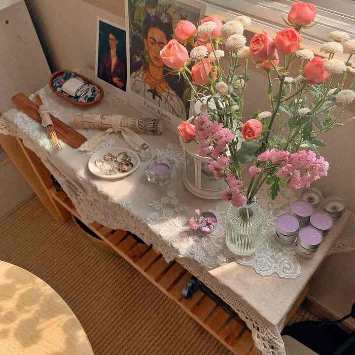 ベージュトーンの棚の上にピンクの花瓶とヴィンテージのレーステーブルクロスが配置された明るい春のインテリア