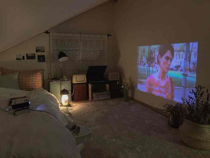 A cozy loft with warm natural tones featuring a bed, vintage audio system, and a projector for a home cinema setup