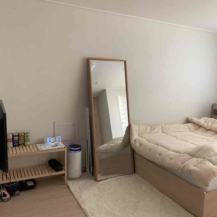 アイボリー色のラグとナチュラルウッドの家具が配置されたワンルーム寝室、シンプルで清潔感のあるインテリア