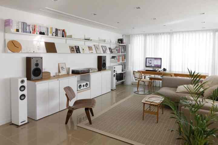 A bright living room in white and natural wood tones featuring a sofa, bookshelves, and minimalist natural modern style