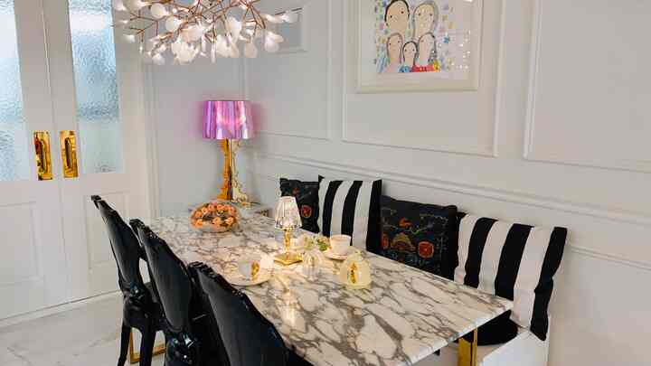 ゴールドと大理石の色調が特徴のダイニング、6人用の大理石ダイニングテーブルと黒いチェア、印象的な照明が配置された優雅な空間