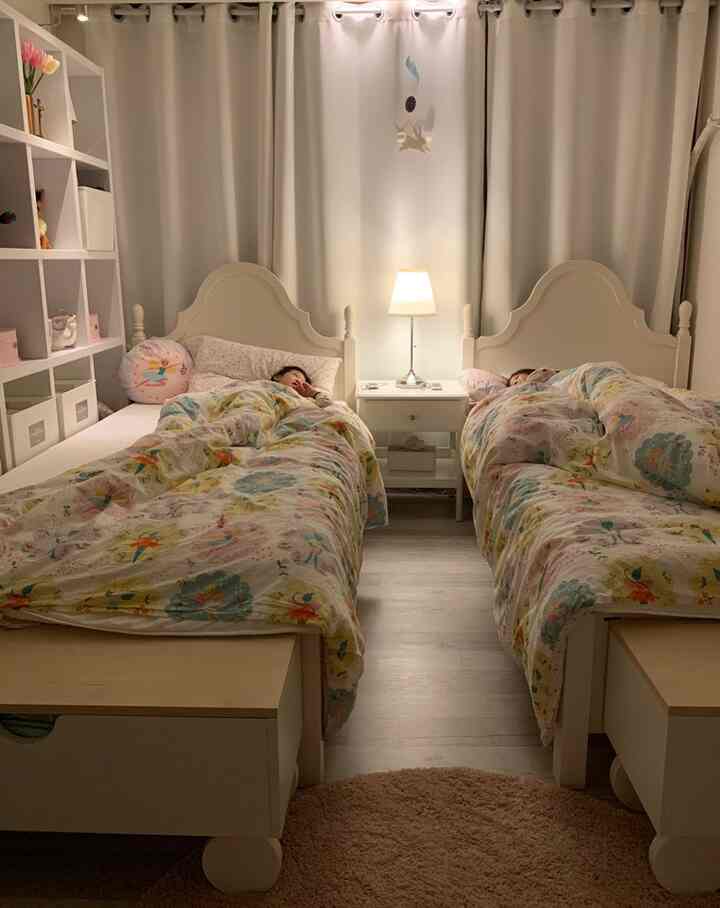 パステル調と白を基調とした子供部屋、2つのベッドとラグ、寝具が可愛らしく配置された寝室のインテリア