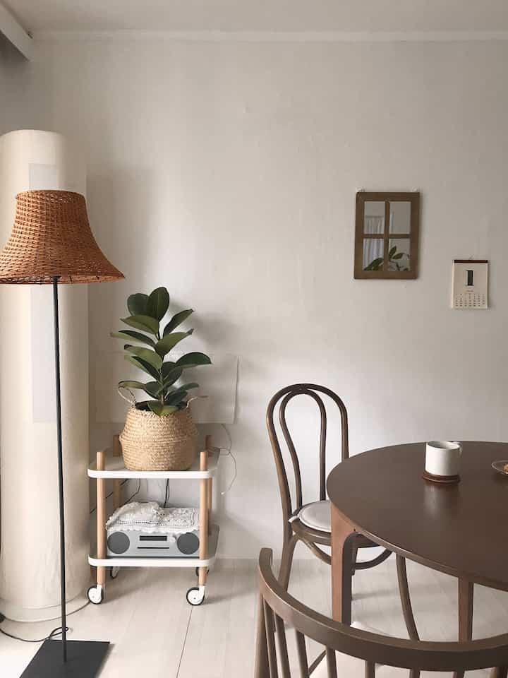 Natural wood tones and rattan lamp blend in a vintage living room dining space