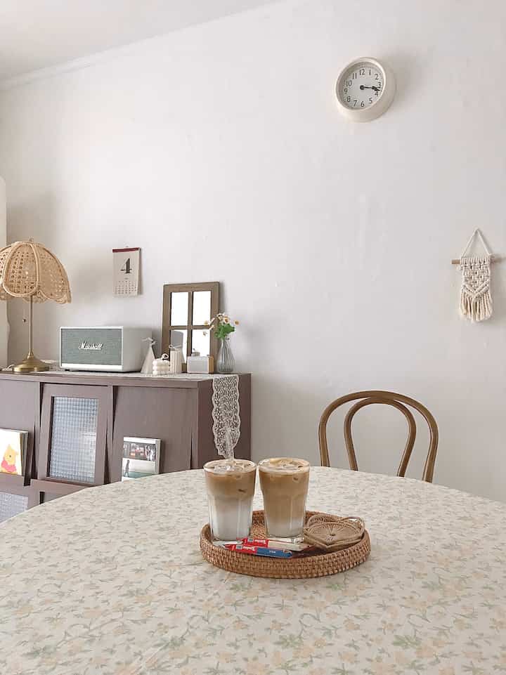 Natural-toned vintage living room featuring a round table with iced lattes and rattan decor, creating a cozy home cafe atmosphere