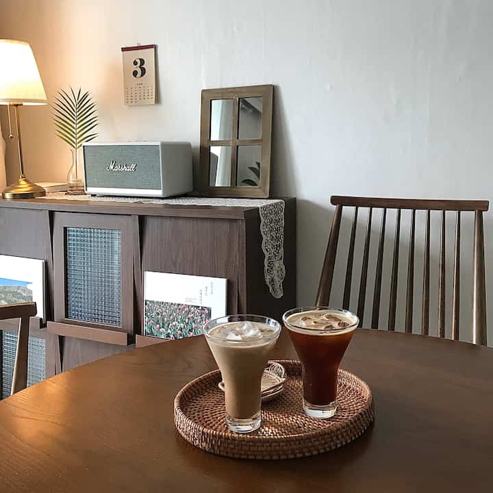 Brown-toned dining room with wooden table and chairs, vintage cabinet and lamp creating a cozy home cafe atmosphere