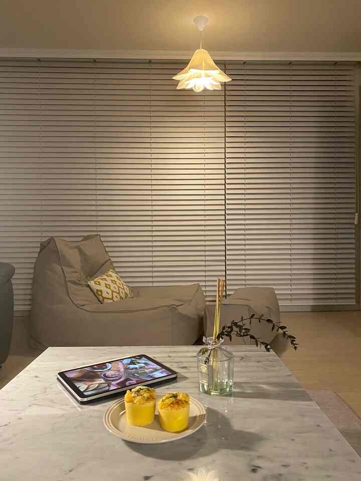 Beige-toned living room featuring a centrally placed bean bag and ottoman creating a cozy evening healing space