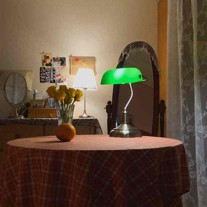 Natural-toned bedroom space featuring an orange round table with a green bank lamp and a visible walk-in closet