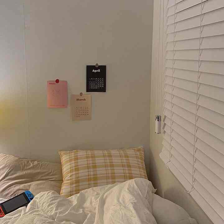 White and beige toned bedroom featuring a bed with a checkered pillow, creating a cozy atmosphere